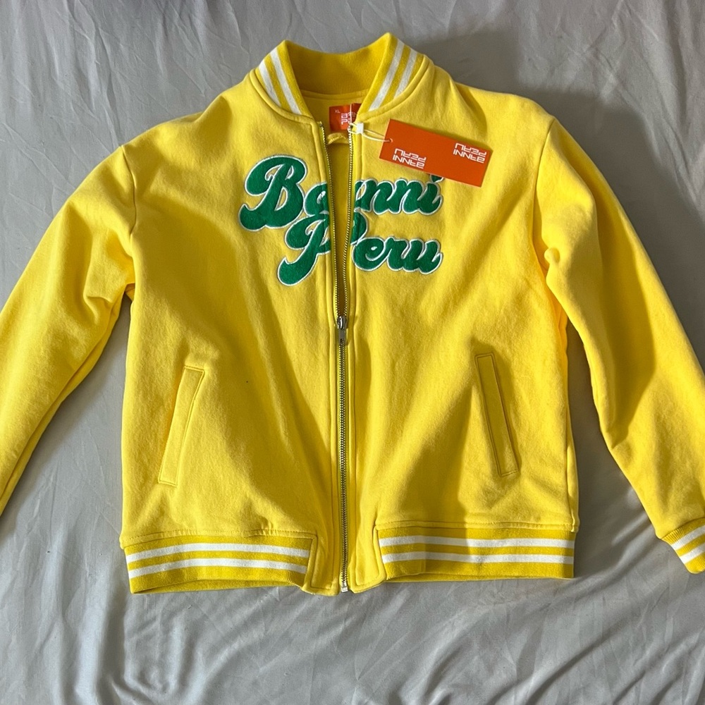Bright yellow BANNI PERU bomber jacket with emerald green writing on the front.